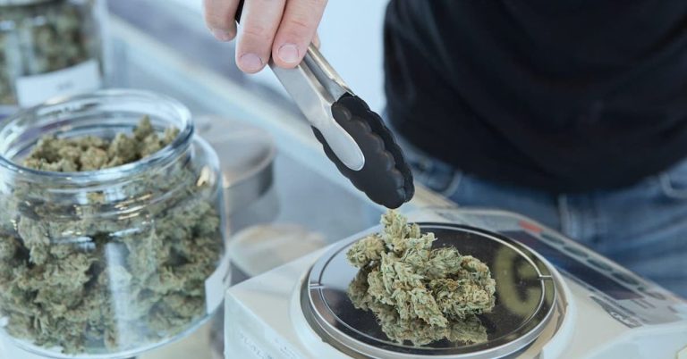 Man using tongs to pick out marijuana buds at a medical cannabis dispensary.
