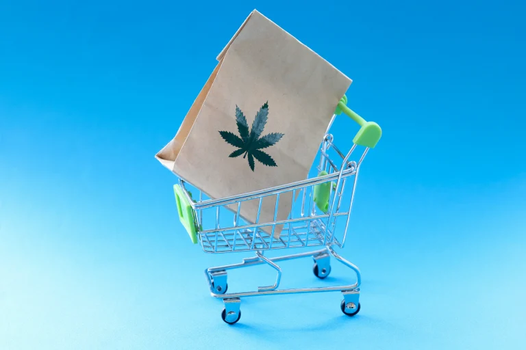 Bag with a marijuana leaf sitting in a miniature shopping cart